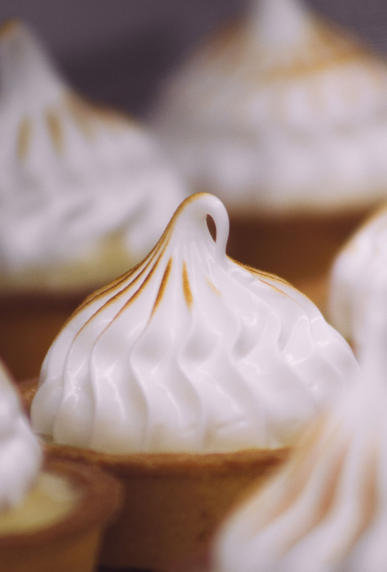 Close-up of gourmet lemon meringue tarts with toasted meringue peaks.